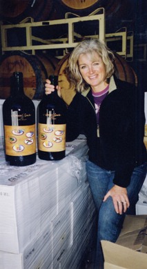 Winemaker Heidi Barrett next to magnums of Amuse Bouche Napa Valley Merlot with label by Wayne Thiebaud